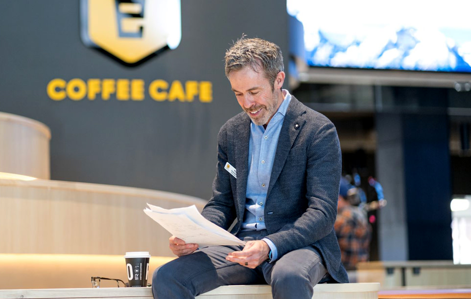 Photo of a person enjoying coffee and reading a newspaper outside the cafe