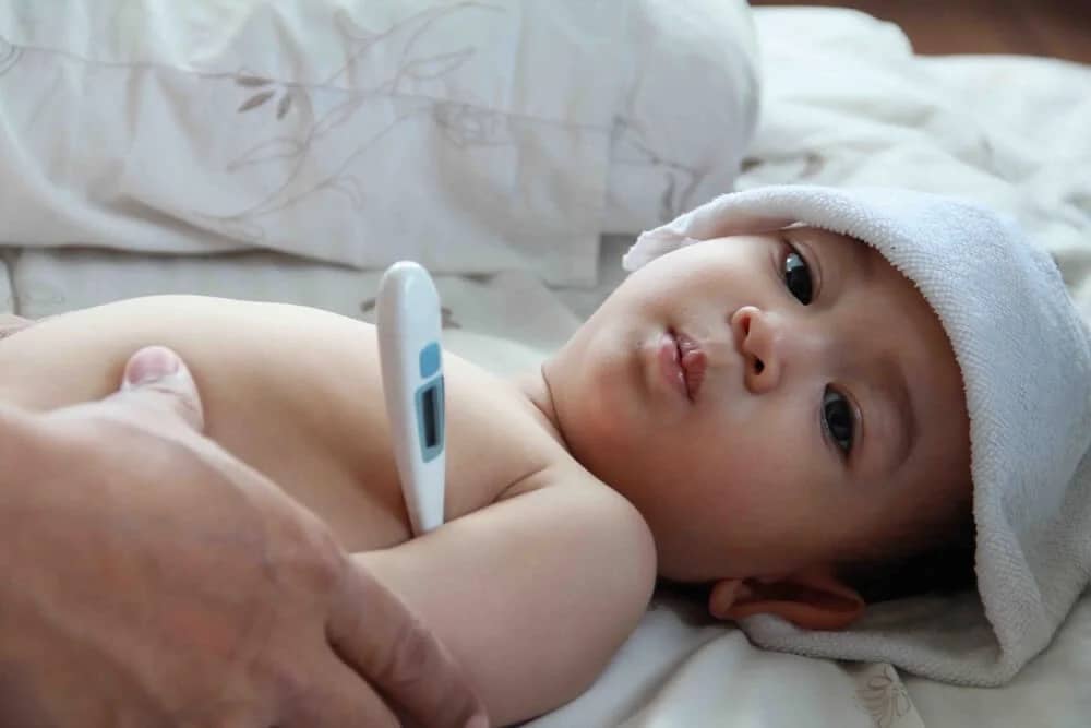 baby's temperature being taken with a thermometer under the armpit