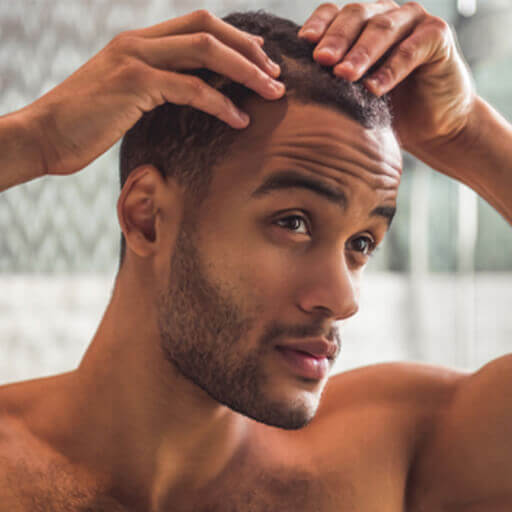 A man checking his scalp for symptoms of hair loss