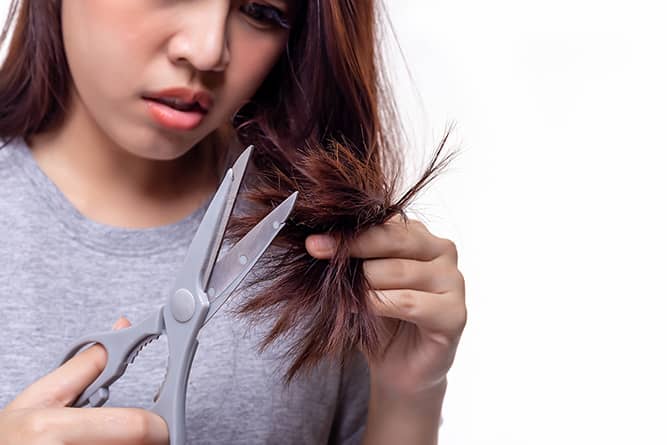 a woman experiencing hair breakage and cutting hair split ends