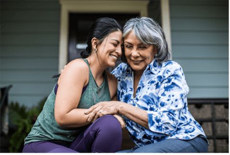 Woman and elderly woman holding, smiling and comforting each other