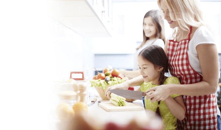 Family smiling, cutting vegetables and cooking together