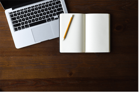 Computer with notebook and pencil on a wooden desk