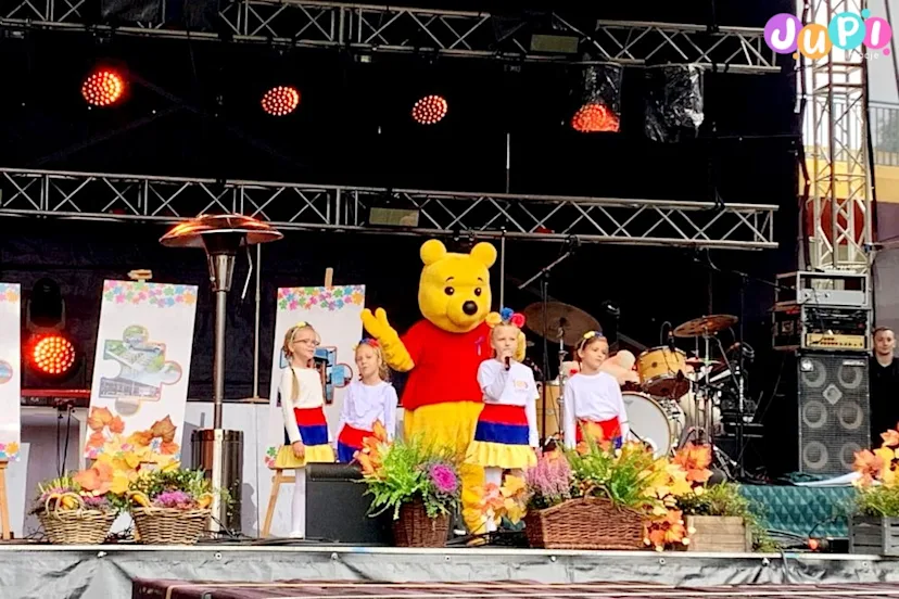 Żywa maskotka miś Kubuś Puchatek na scenie z dziećmi