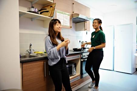 International students talking in shared kitchen in INTO University of Exeter student residences International students talking in shared kitchen in INTO University of Exeter student residences