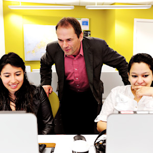 Teacher helps students on flip-top computers in INTO University of Exeter classroom Teacher helps students on flip-top computers in INTO University of Exeter classroom