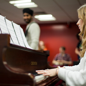 Student playing the piano with sheet music on a music course Student playing the piano with sheet music on a music course