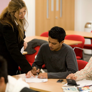 INTO Students at a desk being directed by a teacher INTO Students at a desk being directed by a teacher