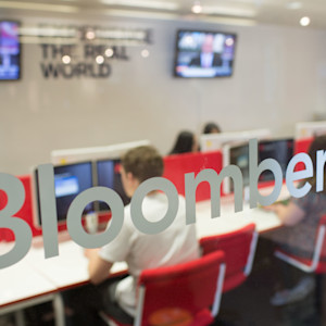 Looking through the glass into a Bloomberg classroom, a group of students are using computers Looking through the glass into a Bloomberg classroom, a group of students are using computers