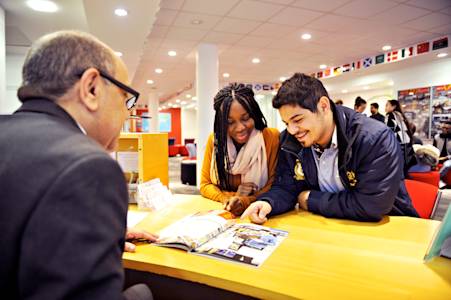 International students at the INTO Centre reception desk looking at University booklet International students at the INTO Centre reception desk looking at University booklet
