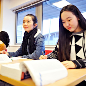 INTO international students learning in a classroom from textbooks INTO international students learning in a classroom from textbooks