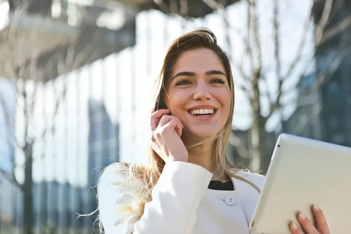 A woman talking on her mobile phone while holding a tablet. Blurred background.