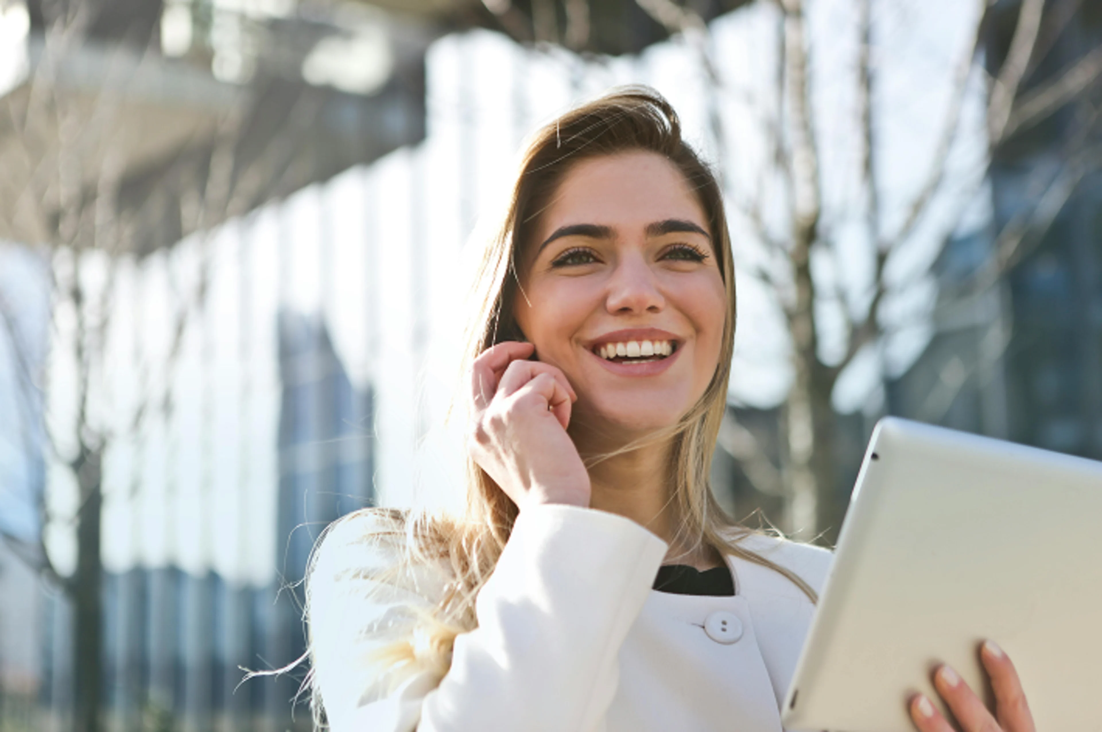 A woman talking on her mobile phone while holding a tablet. Blurred background.