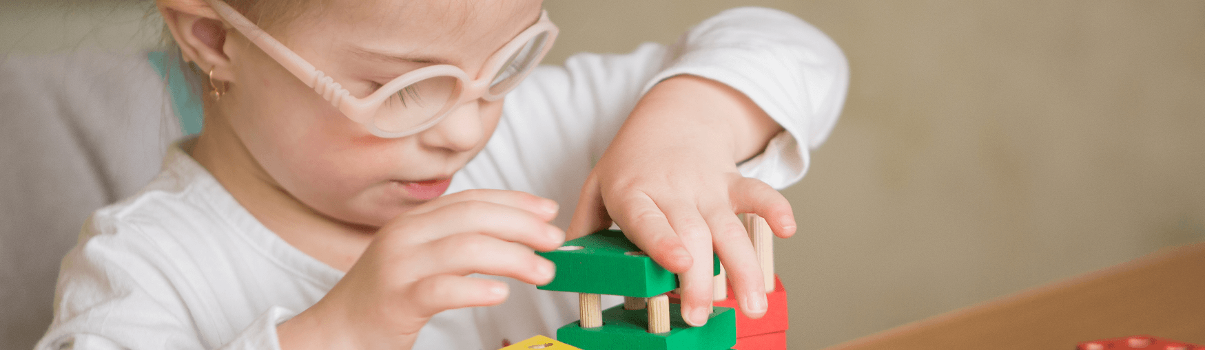 Toddler wearing glasses playing with blocks