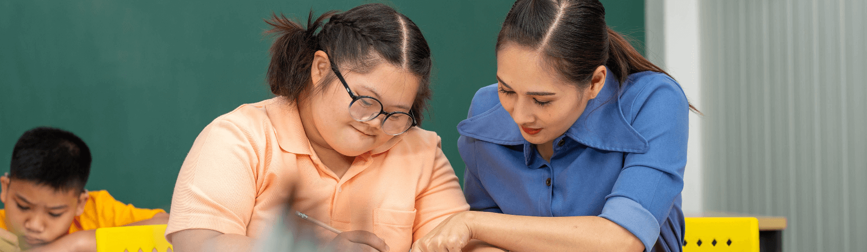 Girl with glasses getting help from female teacher