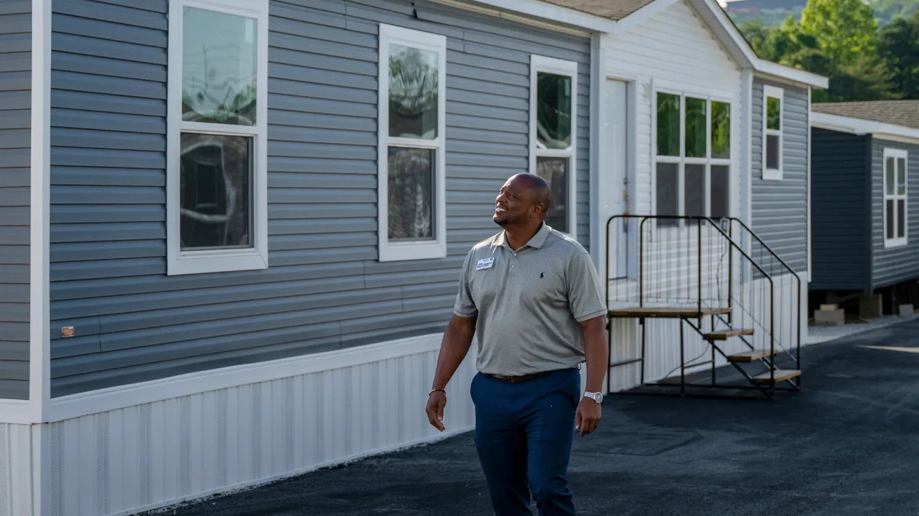 Bryant Moss, a home center manager, walks outside in front of a manufactured home model.