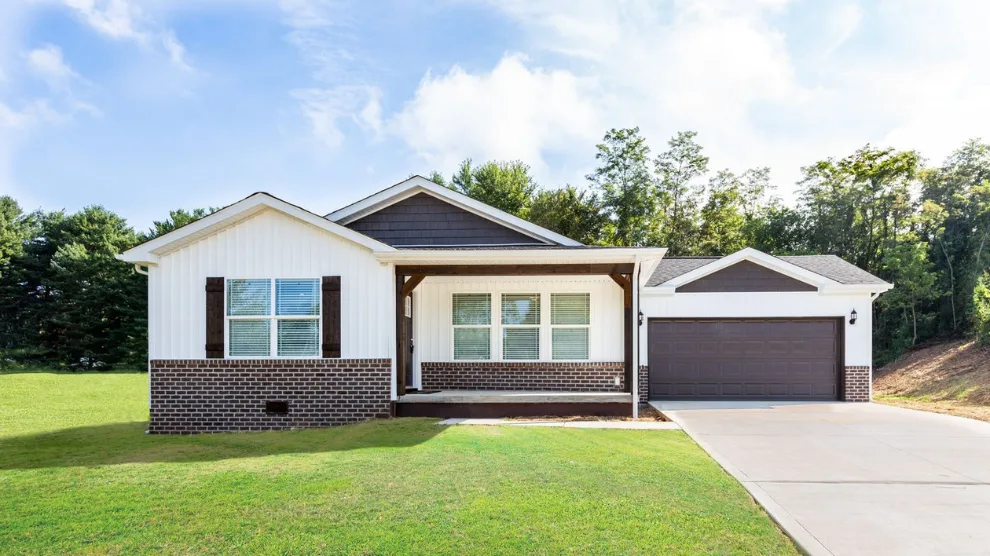 The exterior of the Keenland CrossMod home features white siding with brown details and a front porch, garage and driveway.