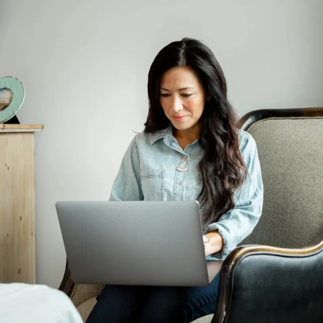 Woman sits inside a new construction home and looking over her finances.