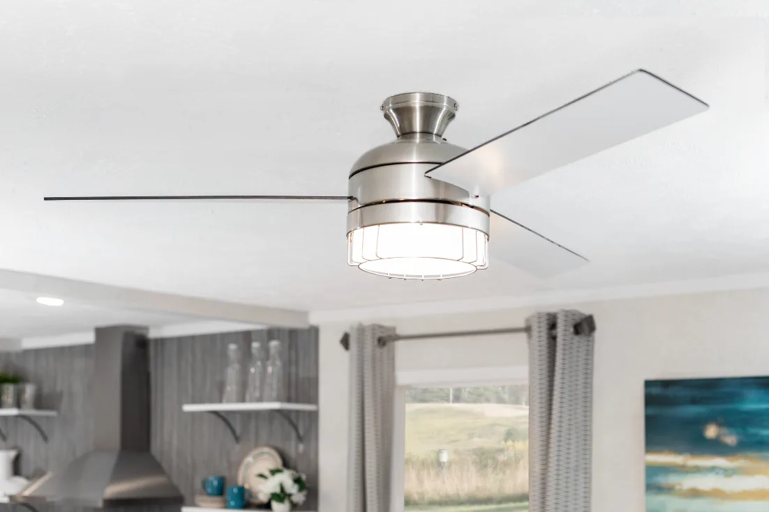 A close-up of a modern ceiling fan with three stainless steel blades.
