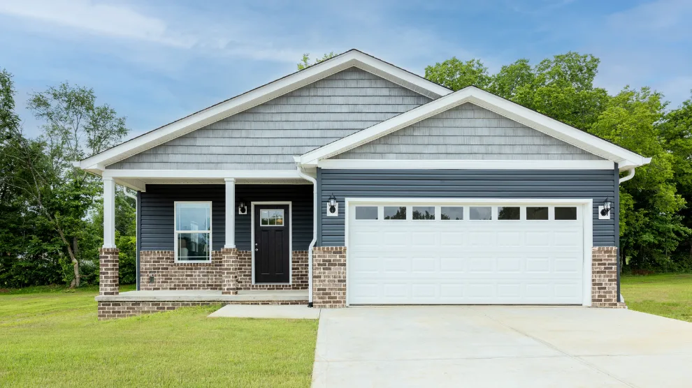 This modern CrossMod home has an attached garage, blue siding exterior and brick facade with front porch views.