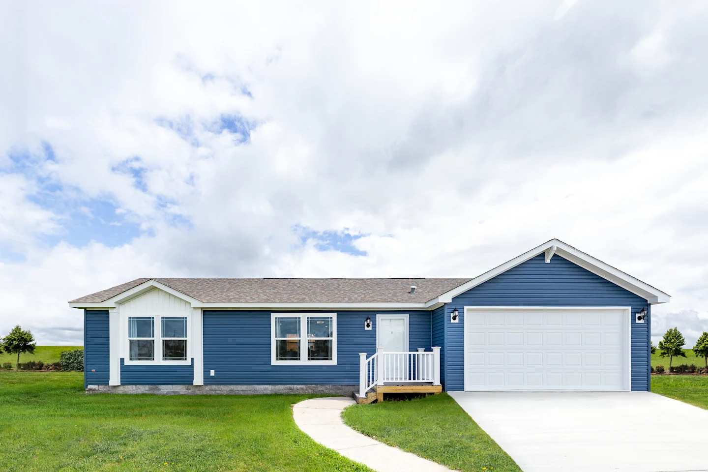 Exterior of manufactured home with blue siding and white doors and window trim.