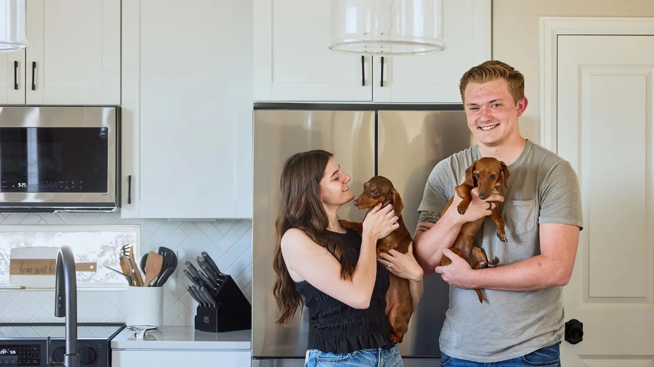 Caidynce and Aidan holding their dachshunds in their kitchen