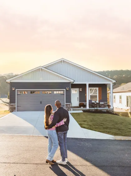 Couple stands outside of their new construction CrossMod home.