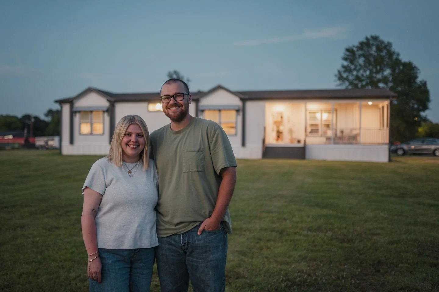 Koven and Josh Bruce standing in front of their Clayton home at dusk.