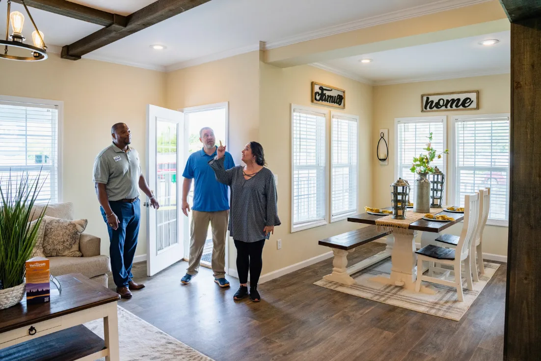 A home consultant and a couple walk into the living room of a model home for a tour.