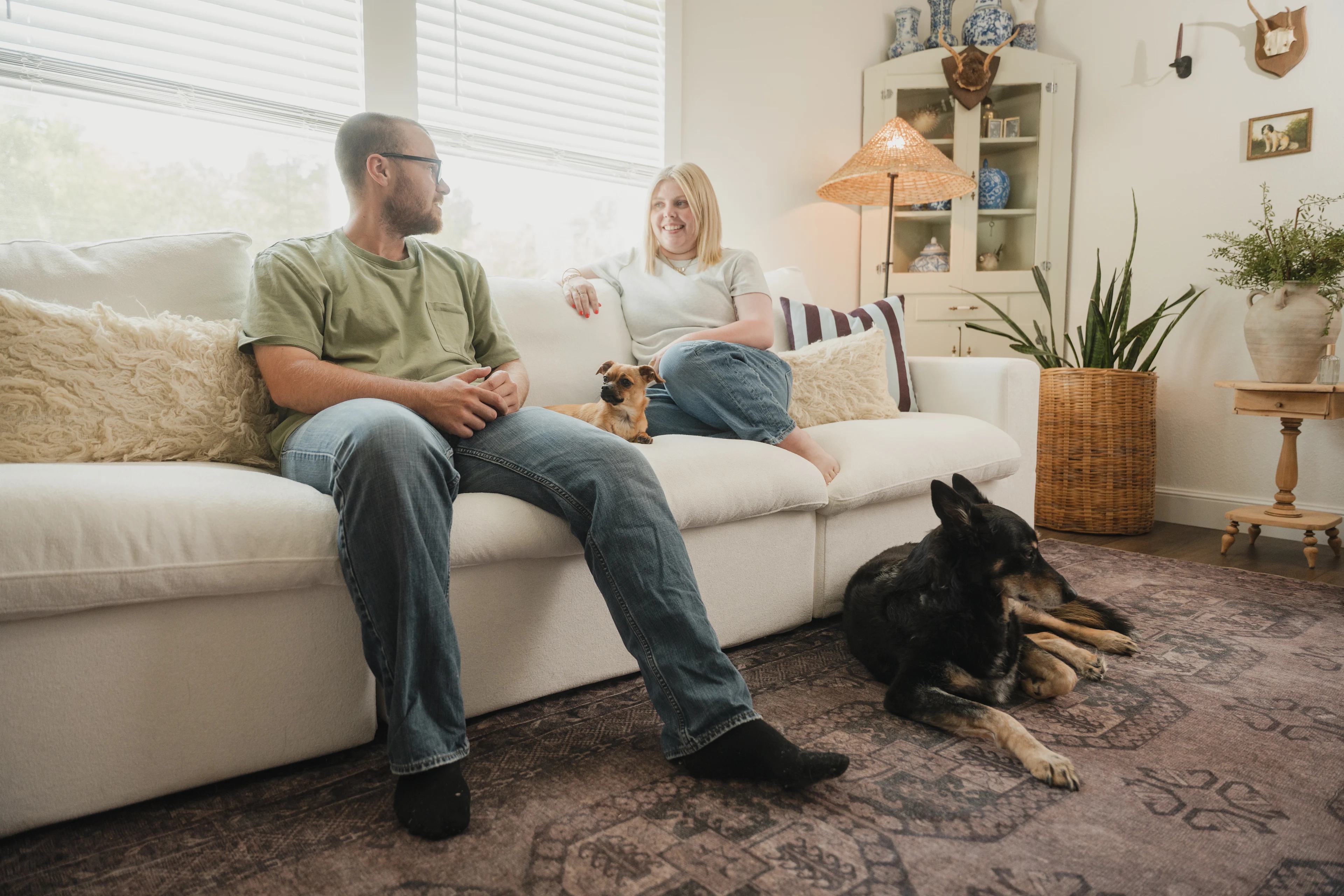 Koven and Josh Bruce sitting in their living room with their dogs Frankie and Lena.