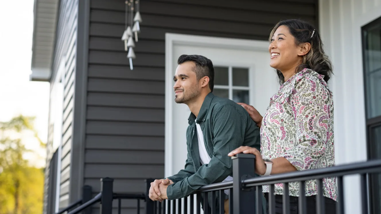 A couple looks out over their front yard from their new construction home porch as they consider their future.