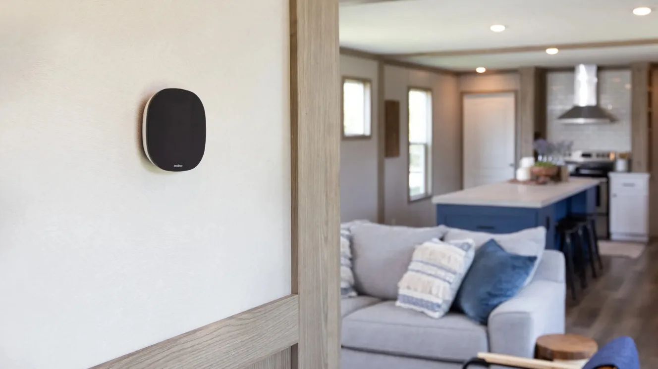 A manufactured home living room with a smart thermostat hanging on the wall.