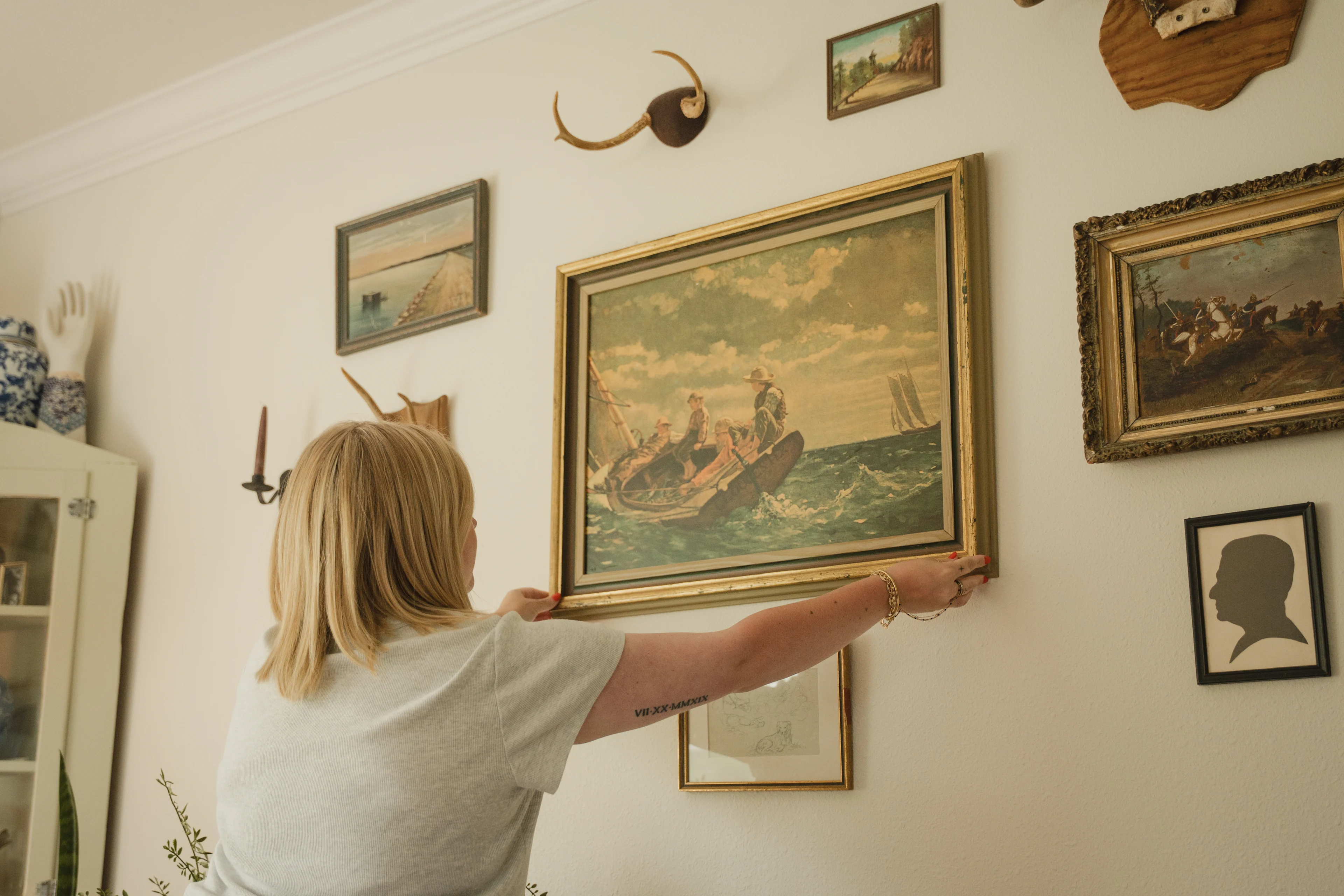 Koven adjusting one of her antique frames on her gallery wall