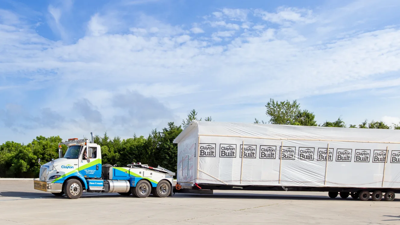 A Clayton Connect truck pulls a section of a manufactured home behind it.