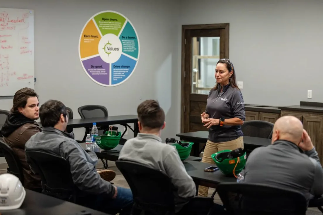 Lisa stands in front of team members in a meeting room.