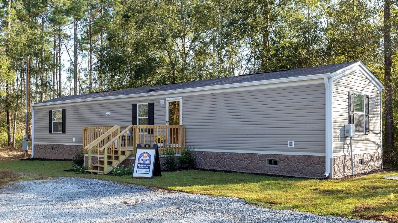 Manufactured home with gray siding and sign out front recognizing it as the tenth home Clayton has donated to nonprofit organization Family Promise. 