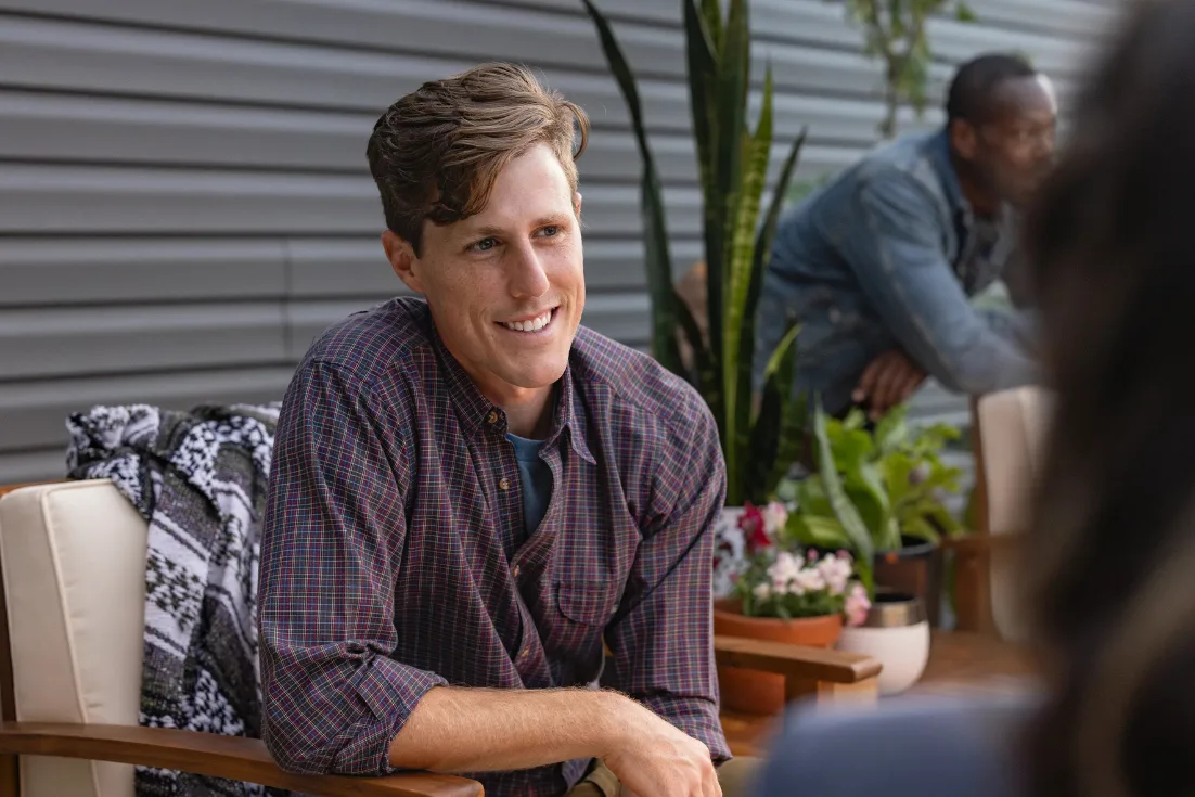 A man sits outside on a patio and speaks to his friends about homeownership and selecting a lender he trusts.