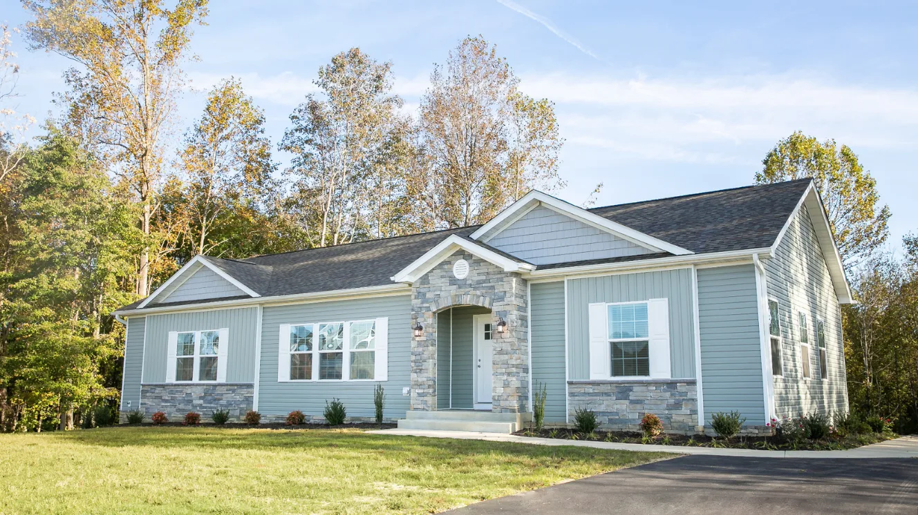 An exterior of a modular home with blue siding, an arched stone entryway, and stone accents.