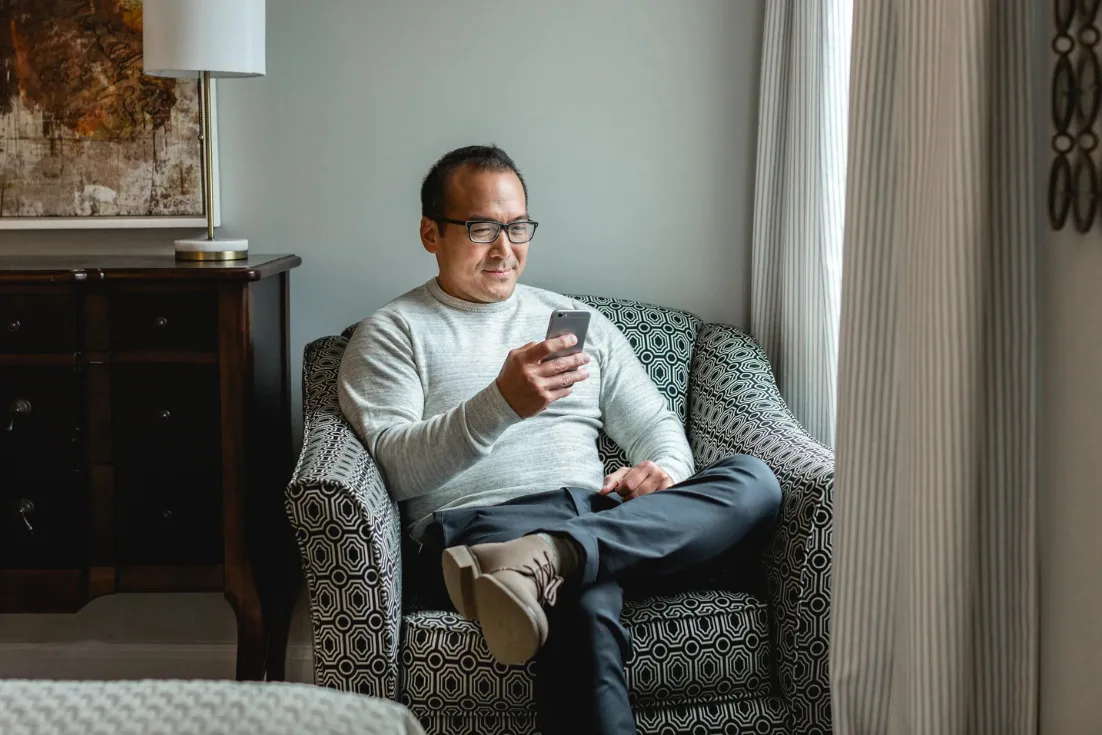 Man sits inside his new construction home from Clayton while shopping online and evaluating lenders of his choice.