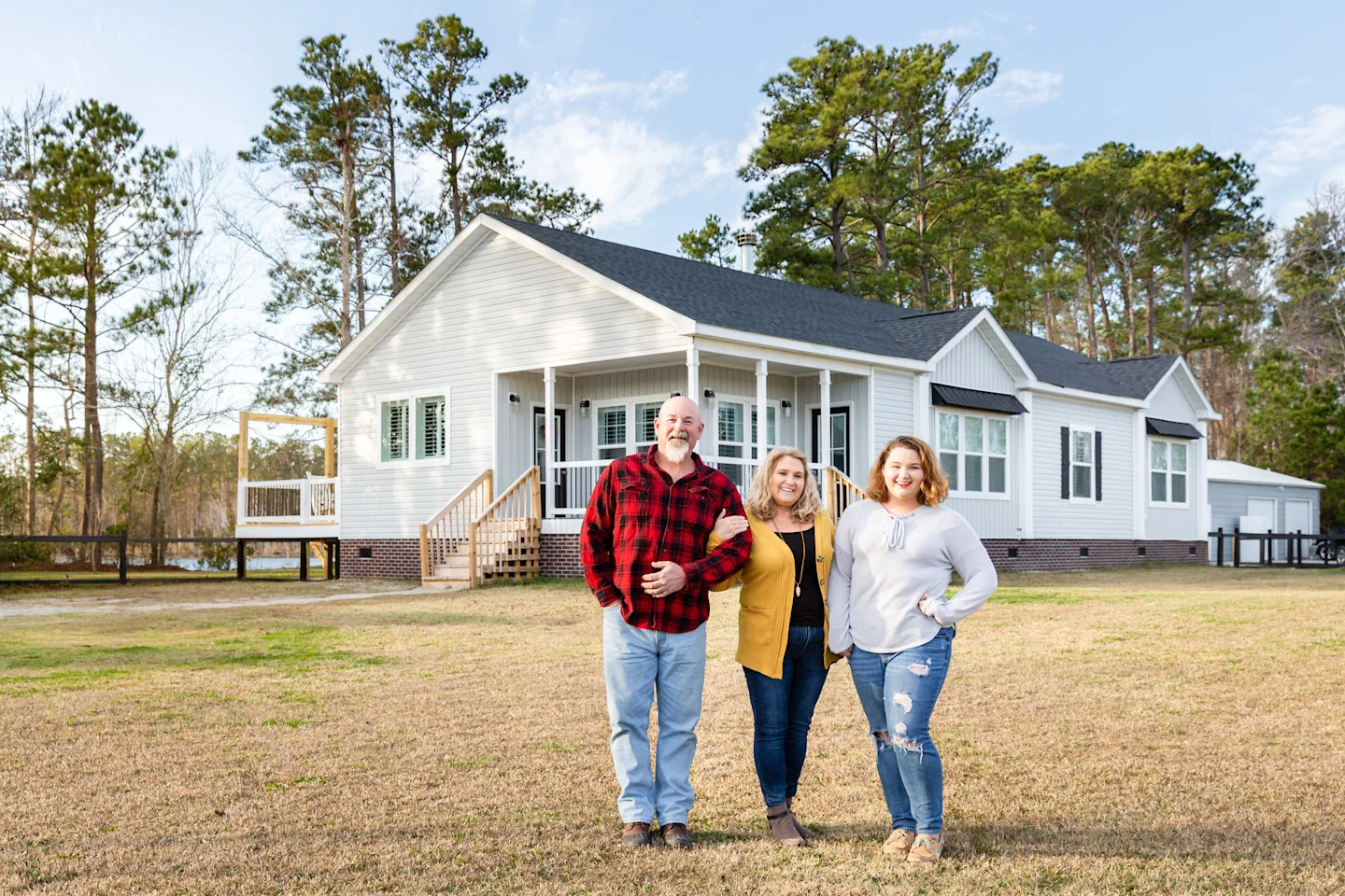 Family stands in front of their new farmhouse home built by Clayton Homes