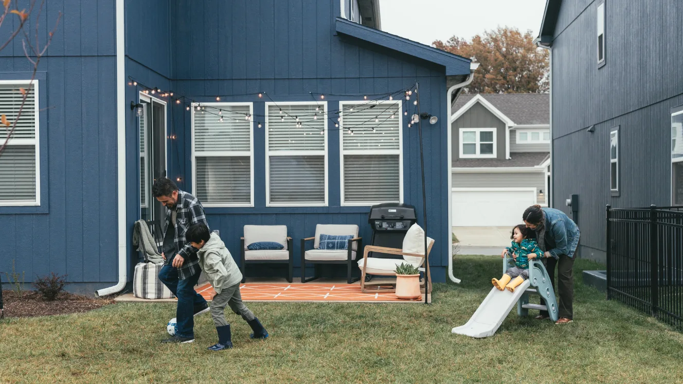 A family plays outside their new construction Clayton home in their backyard in a new build neighborhood.