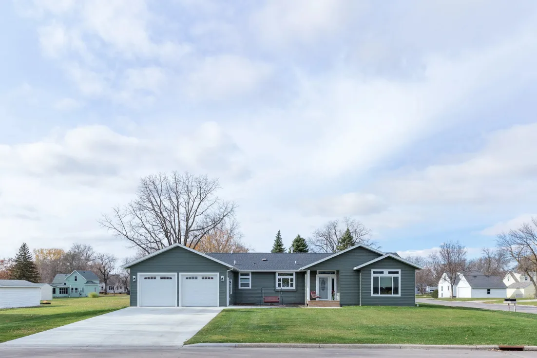 The exterior of a modular home in a neighborhood with gray siding and a two-car garage under a cloudy sky.