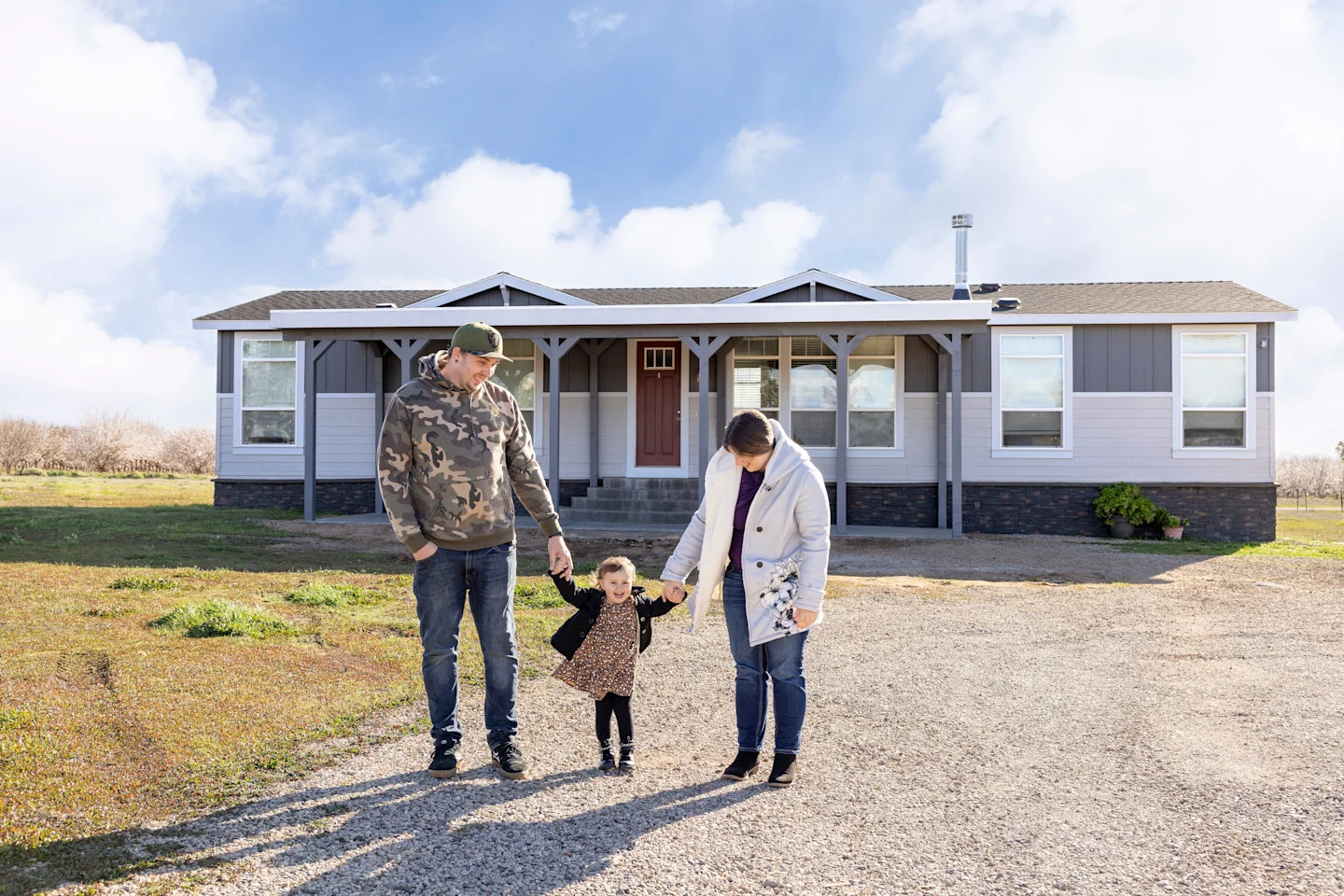  Danica, Jesse and their young daughter Soryah standing in front of their manufactured home.