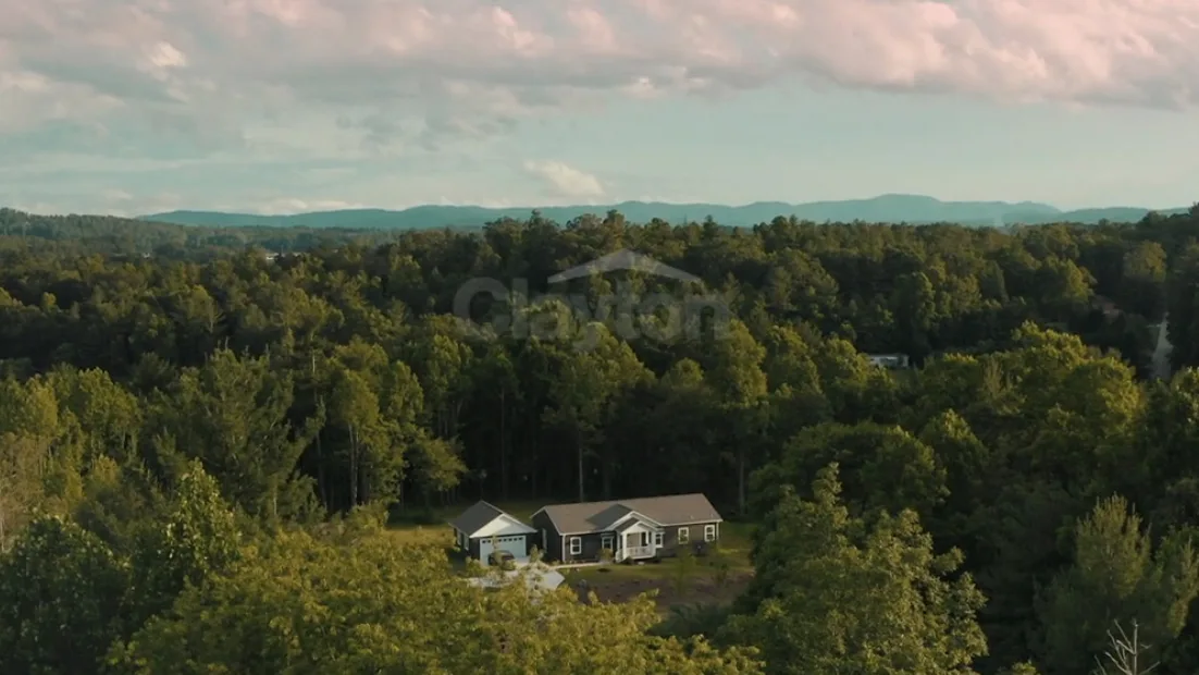 Panoramic view of a CrossMod home on private land surrounded by trees.