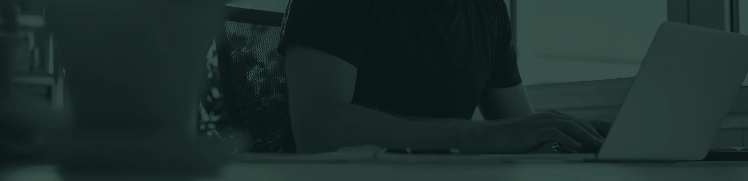 Individual sitting at a desk working on a computer.