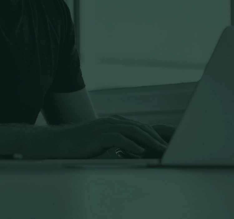 Individual sitting at a desk working on a computer.