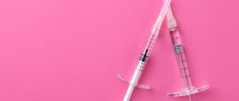 Syringes against a bold pink background.