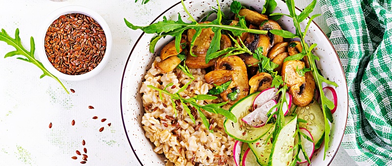 Breakfast oatmeal porridge with green herbs on mushrooms, cucumber, radish and flax seeds.