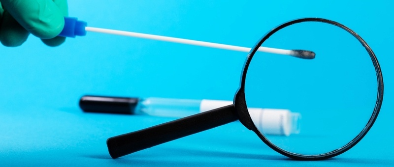 Doctor allergist holds a sterile probe with allergy tests against a magnifying glass on a blue background. 