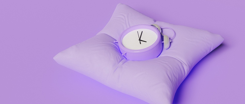 Purple alarm clock face-up on a purple pillow against a purple background.
